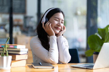 Attractive young Asian woman relaxing from work during break listening to music and having fun.