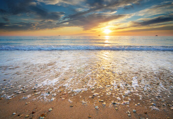 Sand and rocks on seashore at sunset