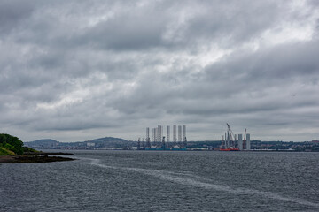 The view of the Port of Dundee from Tayport the other side of the Tay Estuary on a dark Rainy day in July with Oil Rigs lining the Wharfs of the Port.