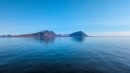 Beautiful mountains at the coastline of Svalbard on a sunny day with calm sea - Landscape Photography