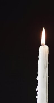 Vertical video of lit candle and copy space on black background