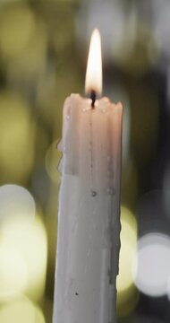 Vertical video of lit candle and copy space with bokeh on black background