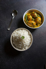Cooked food rice and egg curry served in bowls. Top view, selective focus.