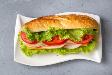 Cheese, ham, lettuce and tomato slices in an appetizing tasty sandwich.