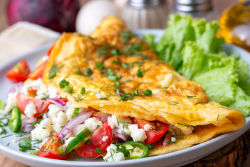 Homemade stuffed omelet on a plate. Egg omelet stuffed with fresh tomatoes, cheese and green parsley. Healthy vegetarian breakfast recipe.