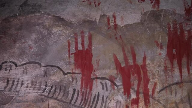 Red creepy prints of bloody hands on an old wall in a dark creepy room. Quest room for adults. Creepy paint marks on the old wall. A prison cell.