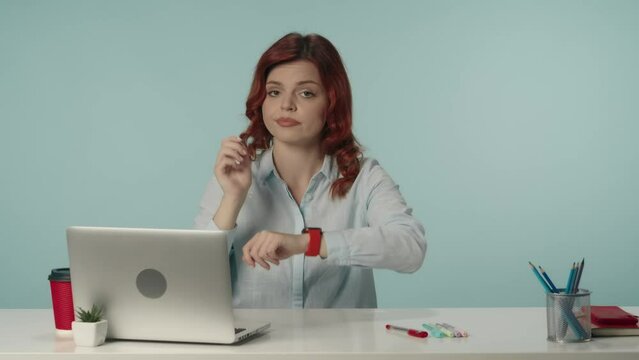 Medium isolated video of a young woman pointing at her watch and negatively wagging her finger to show her complaint about overworking.