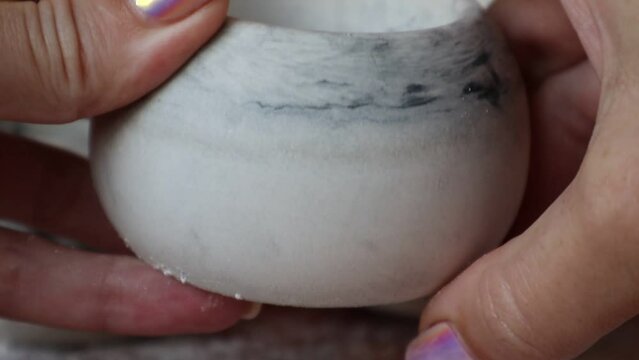 A girl cleans a round candle mold of plaster crumbs. High quality video