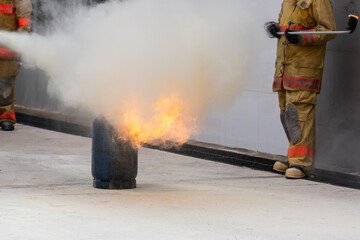 Obraz premium Showing how to use a fire extinguisher on a training fire for employees industry.Firefighter working on the fire site.Fire fighter concept.