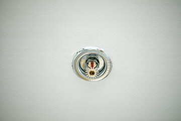 Sprinkler mounted on the ceiling with a white background. Close-up. © Qooz 