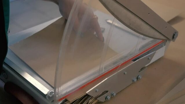 Use Paper Cutter. Woman uses the cardboard cutter to cut jagged cardboard ends