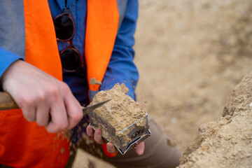 Mains d'une archéologue faisant un prélèvement de terre pour examen - obrazy, fototapety, plakaty