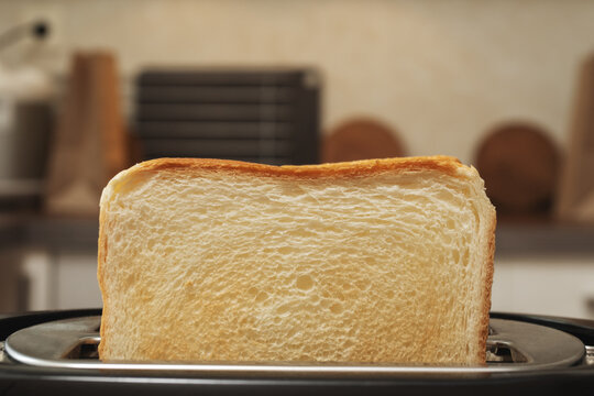 toasted bread slices popping up from the toaster, toaster on the kitchen preparing crispy toast for healthy breakfast.