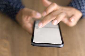 Screen of mobile phone in female hands over table surface. Young business woman touching display of smartphone, using online application, service, digital gadget for Internet communication. Close up