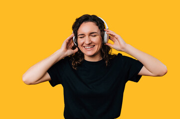 Happy young woman is listening to the music or podcast in wireless headphones.