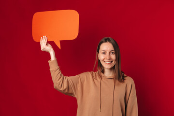 Studio portrait of a young smiling woman holding an orange bubble speech.