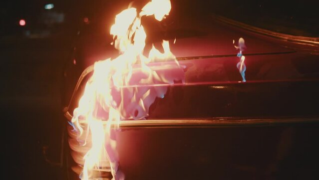 Criminal setting fire to a car. Person destroying other people's property, The fire spreading through the automobile.