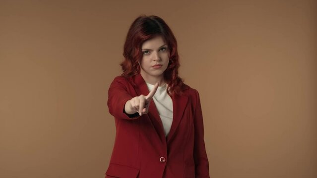 Medium isolated video of a young woman pointing at the camera and negatively wagging her finger to show her disagreement, complaint about something.