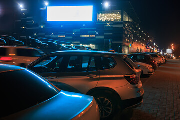 Cars in the parking lot at night in the city near the shopping center
