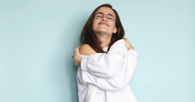 Come into my arms. Adorable happy girl with brown hair in pullover gesturing come here for free hugs and smiling sincerely with welcoming expression isolated on blue background.