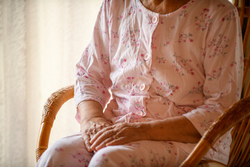 パジャマ姿で籐椅子に座る高齢の女性