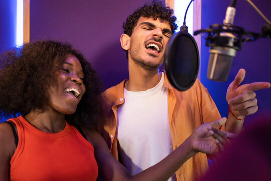 Man and black woman singing and recording song together