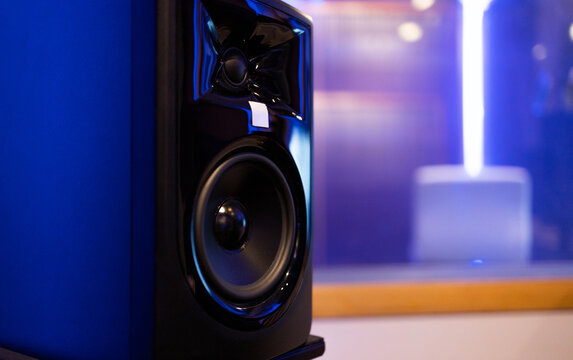 Loud speakers enclosed in black studio monitor placed on table in blurred room