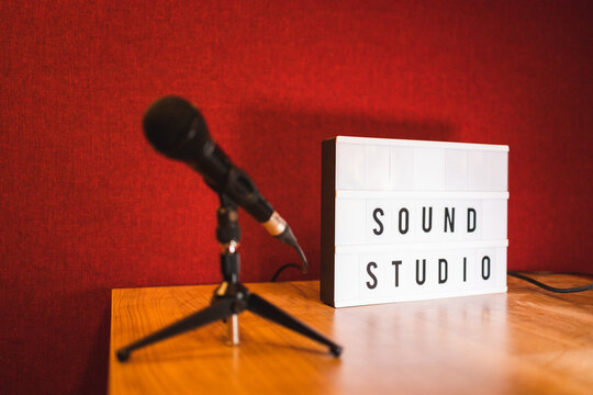 Microphone on tripod and signboard with words sound studio placed on table in reflecting light