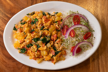 Appetizing scrambled fried egg and sprouts with red onions and tomatoes in plate