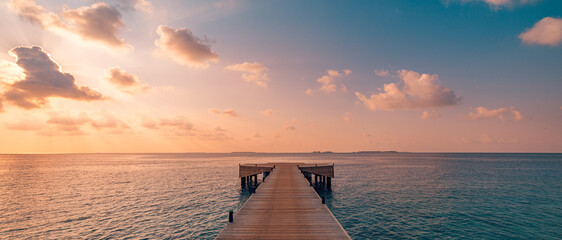 Beautiful seascape long jetty pier at sunset. Minimal sea sky, calm water surface and reflections. Colorful peaceful sunrise tones orange, gold, blue. Tranquil relaxing panoramic inspire meditation