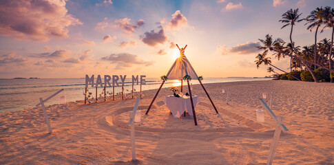 Love couple romantic proposal on paradise beach in island Maldives. Panoramic sunset of Marry Me sign at beach background. Romance colorful sky sea. Marriage proposal, honeymoon tropical destination