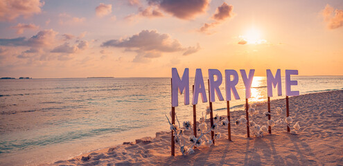 Love couple romantic proposal on paradise beach in island Maldives. Panoramic sunset of Marry Me sign at beach background. Romance colorful sky sea. Marriage proposal, honeymoon tropical destination