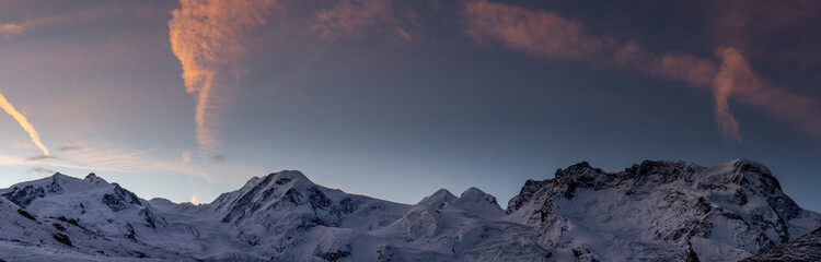 Snowy mountains in winter day under dark blue sky at sunrise