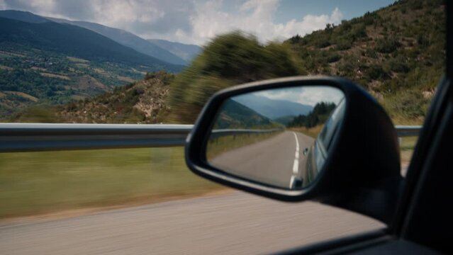 Vacation road trip vehicle rearview mirror on mountain road in movement
