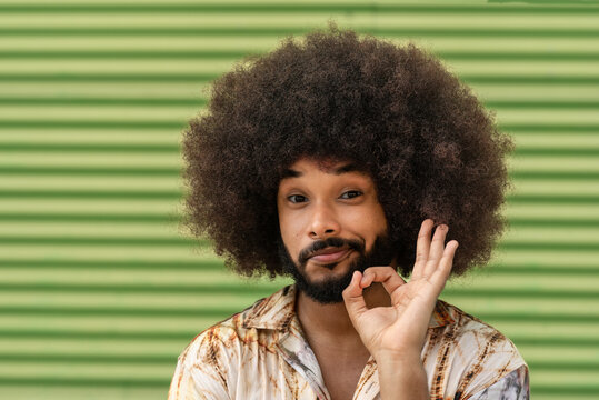 Smiling black man showing OK gesture against wall