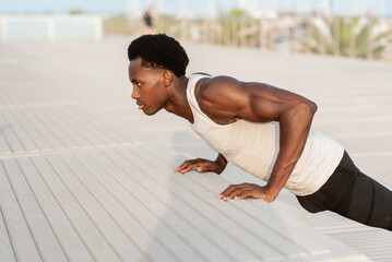 Black man doing push ups on embankment