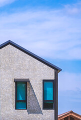 Two casement glass windows on concrete loft wall of vintage house in modern industrial style against blue sky background in vertical frame