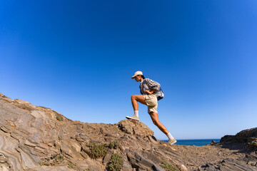 tourist girl with a backpack on her back climbs the mountain in summer