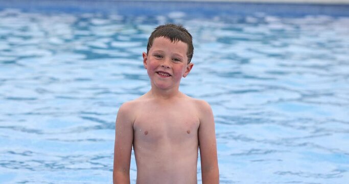 Cheerful cute kid standing in swimming pool 