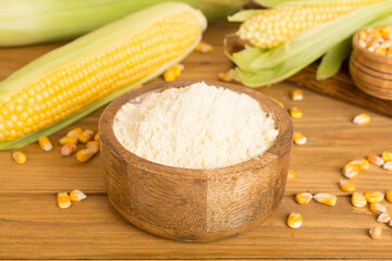 Corn flour with fresh cobs on wooden table