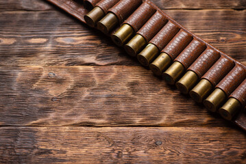 Old cartridge belt with empty brass sleeves on wooden table background. Hunting concept background with copy space.