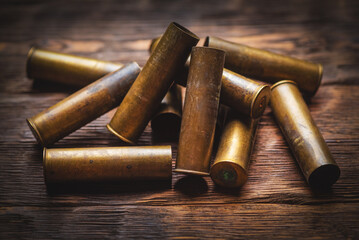 Bunch of old brass gun shells wooden table background close up. Hunting concept background. - Powered by Adobe