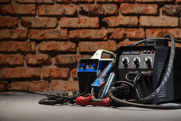 Welding concept background. Semi automatic welding machine and plasma cutter close up on the floor...
