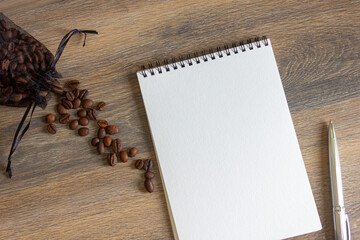 Notepad and coffee beans scattered on the wooden table