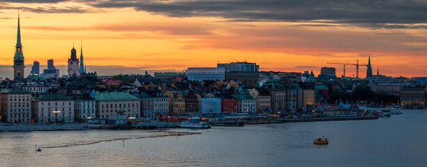 Panoramic view of Stockholm's old town, churches and seafront on a summer evening, with orange sky...