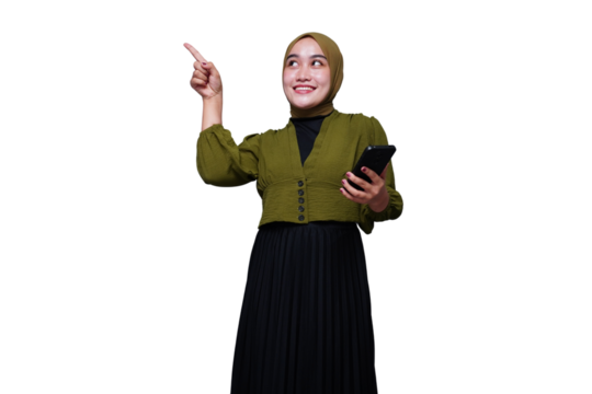 Smiling asian hijab woman pointing at something while holding phone
