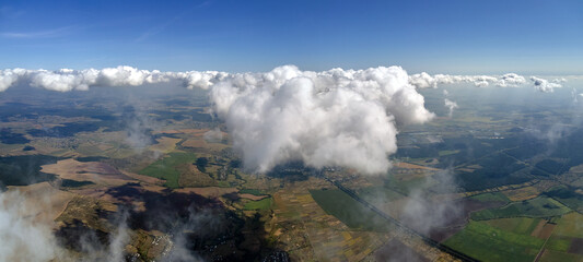 Aerial view from airplane window at high altitude of earth covered with white puffy cumulus clouds