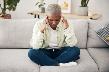 Stress, headache and pain with a black woman on a sofa in the living room of her home for mental...