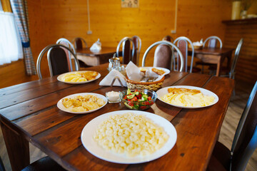 Wooden table with plates with simple dishes. Dining room menu.