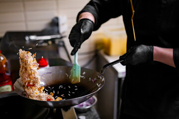 Chef cooking stir fry rice and chicken in wok pan at restaurant kitchen.